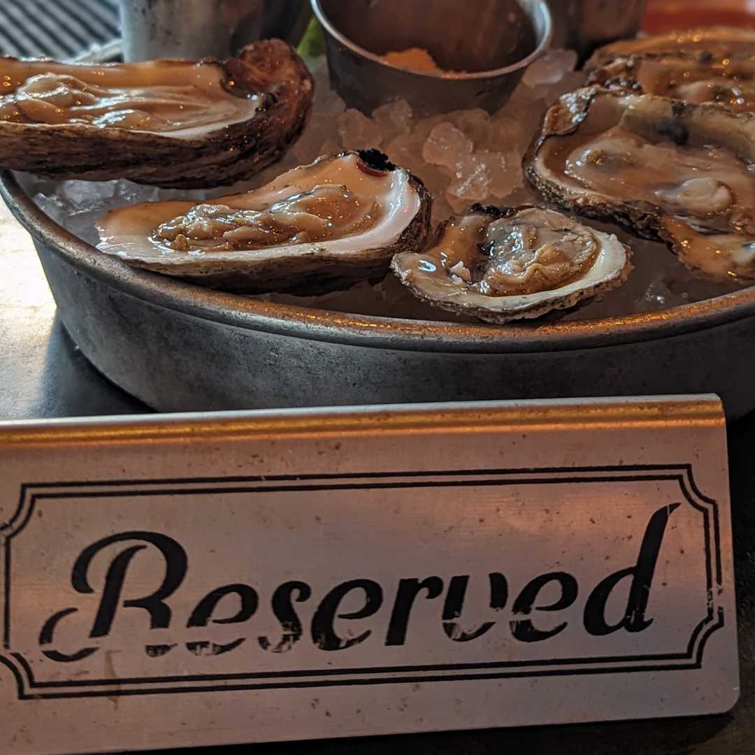 Reserved" sign sitting in front of a bowl of fresh oyster shells, reflecting the coastal culinary culture of downtown Charleston